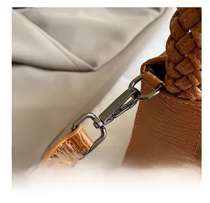 Macro view of gunmetal hardware and hand-woven handle on brown pebbled leather bag
