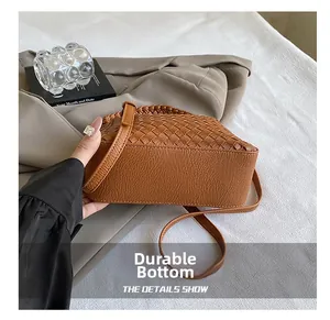 Detailed view of the durable woven base and reinforced stitching of the brown leather bag