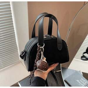 Detail van een zwarte leren Boston tas met dubbele rits en een schattige bruine hanger