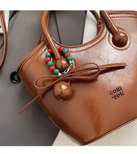 Gros plan du sac seau en cuir marron vintage avec charms en perles et nœud