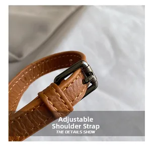 Detail of adjustable brown leather shoulder strap with visible stitching and metal buckle