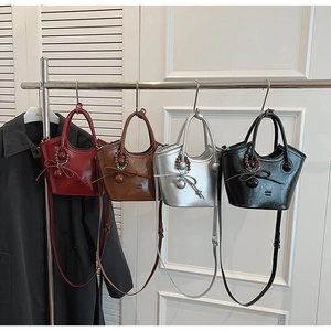 Détail de quatre sacs seaux en rouge, marron, argent et noir avec des nœuds décoratifs