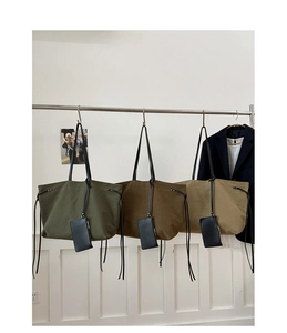 Three canvas tote bags in green, brown and khaki hanging with small leather pouches
