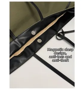 Detail of magnetic snap closure on olive canvas tote bag with leather trim accents