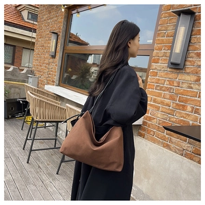 Grand sac cabas en toile marron avec de fines anses noires porté par un mannequin en extérieur