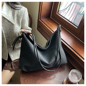 Détail d'un grand sac cabas en cuir souple noir avec nœud latéral et doubles anses