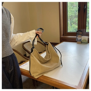 Détail du sac à bandoulière minimaliste en similicuir suédé abricot sur table marbre