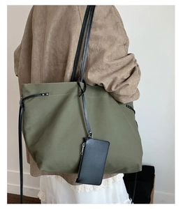Olive green canvas tote bag detail featuring black leather straps and a mini coin purse