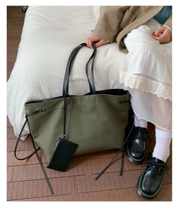 Olive green canvas tote bag with black leather straps and matching hanging pouch detail