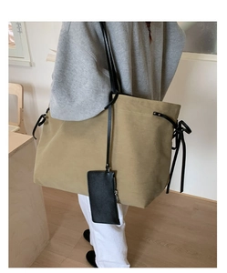 Detail of khaki tote bag with black slim straps and matching small zippered pouch