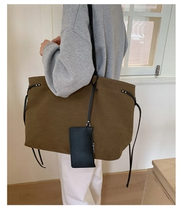 Detail of olive brown canvas tote bag with black strap and hanging coin purse accessory