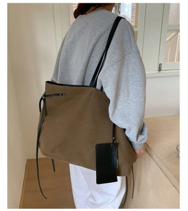 Dettaglio della borsa tote in tela vintage con tracolla in pelle e piccola borsa appesa