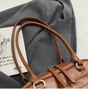 Detail of vintage brown leather underarm bag with long straps and long zipper pulls