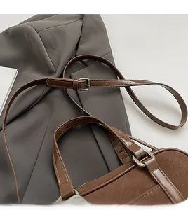 Close-up of brown suede Boston bag strap with silver metal buckle on grey blazer