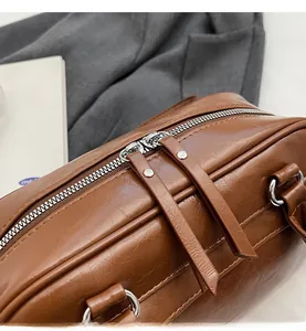 Detail of smooth silver double zippers on textured brown leather underarm bag