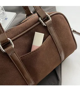 Detail shot of front pocket on brown suede bowling bag showing storage space