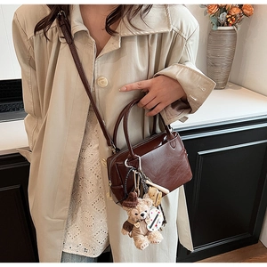 Détail du sac à main en cuir marron foncé avec breloques de luxe et pendentif ourson