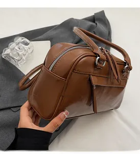 Close-up of a dark brown oil-wax leather Boston bag featuring silver-tone dual zippers