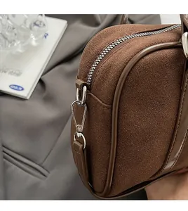 Detail of matte brown shoulder bag featuring polished silver metal hardware and leather trim