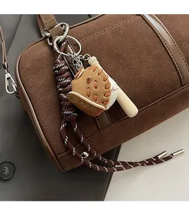 Detailed close-up of baseball charm accessory with mini glove and bat on suede handbag