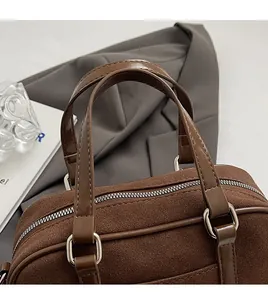 Detail of dark brown suede bowling bag with leather handles and silver hardware