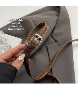 Close-up of adjustable brown leather shoulder strap with silver metal buckle on a retro bag