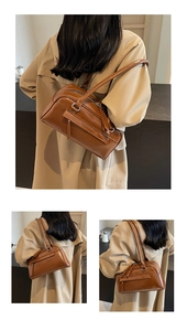 Close-up of vintage brown leather underarm bag with zipper tassel and dual handles