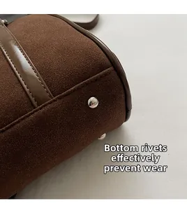 Detailed macro view of dark brown suede bag base with protective silver metal rivets