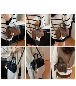 Détail du sac bowling en daim avec breloques rétro et bandoulières en cuir élégant
