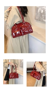 Macro detail of dark red glossy patent leather handbag featuring bow-tie pocket accents