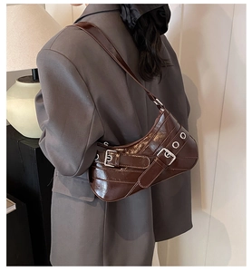 Détail du sac baguette en cuir verni marron foncé avec boucles et œillets argentés