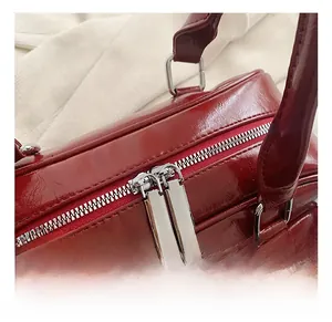 Detailed close-up of high-quality silver double zippers on vintage red PU leather handbag