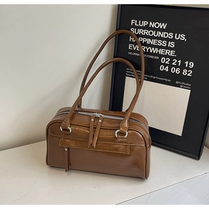 Detail of vintage brown leather underarm bag with dual metal zippers and polished finish
