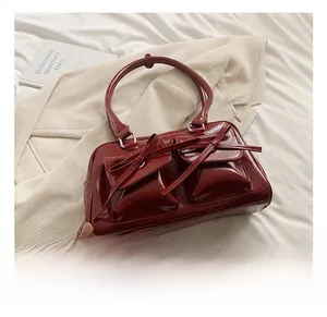 Detail of burgundy PU leather bowling bag with twin bow-knot flap pockets and glossy finish