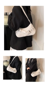 Detail of white half-moon underarm bag with silver buckles and decorative cross straps