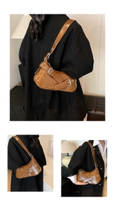 Detail of caramel glossy baguette bag with metal eyelets and adjustable strap