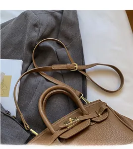 Detail of caramel lychee leather handbag with adjustable strap and gold hardware