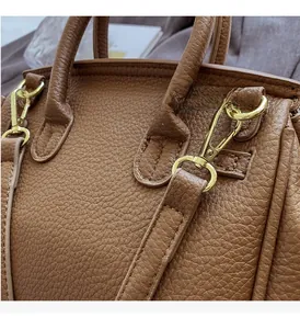 Detail of brown lychee leather handbag with gold hardware and cylindrical handle