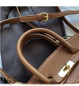 Detail of brown litchi pattern leather handbag with gold hardware lock and handle