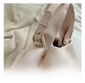 Detail of pink lychee leather handbag featuring golden metal rings and sturdy rivets