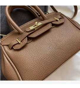 Detail of brown lychee grain leather handbag with gold metal clasp and top handle