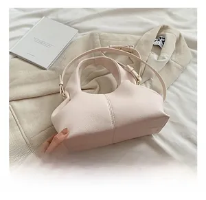 Detail showing light pink pebble leather texture and curved stitching on handbag