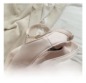 Detail of light pink pleated cloud bag showing pebbled leather texture and gold hardware