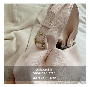 Detail of adjustable shoulder strap with gold metal buckle on light pink leather handbag