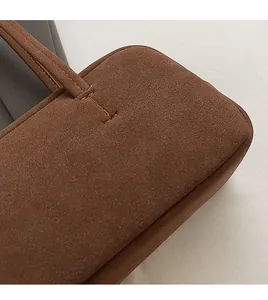 Makro-Detail der braunen Wildledertasche zeigt präzise Nähte und weiche Textur