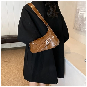 Detail of a brown glossy leather shoulder bag with vintage buckles and metal eyelets