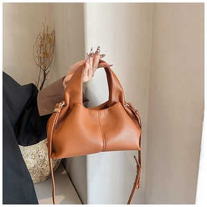 Sac nuage en cuir marron avec grain naturel, tenu par un mannequin en décor épuré