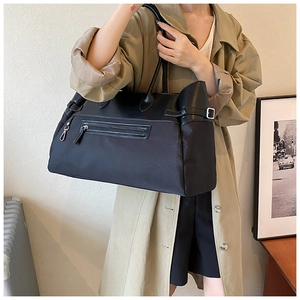 Detail of classic black nylon tote bag with leather straps and side buckle adjustment