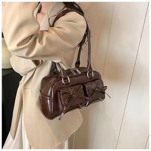 Detail of dark brown glossy PU leather bag with bows and two front flap pockets