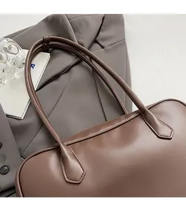 Détail des longues poignées cylindriques et coutures solides sur un sac fourre-tout